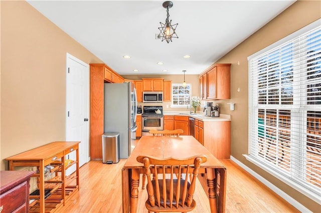 kitchen featuring light countertops, recessed lighting, appliances with stainless steel finishes, light wood-style floors, and hanging light fixtures