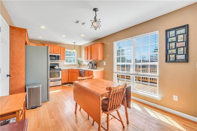 kitchen with light wood finished floors, visible vents, light countertops, hanging light fixtures, and stainless steel appliances