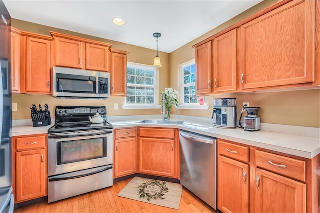 kitchen with a sink, light countertops, light wood finished floors, and stainless steel appliances