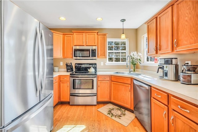 kitchen featuring a sink, stainless steel appliances, light wood-style floors, and light countertops