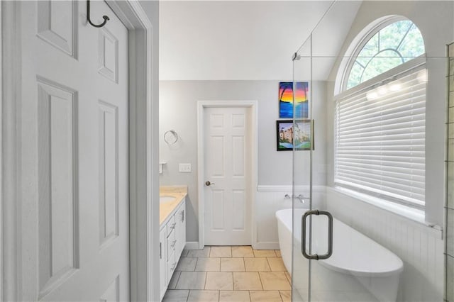 bathroom featuring wainscoting, a freestanding bath, vanity, and vaulted ceiling