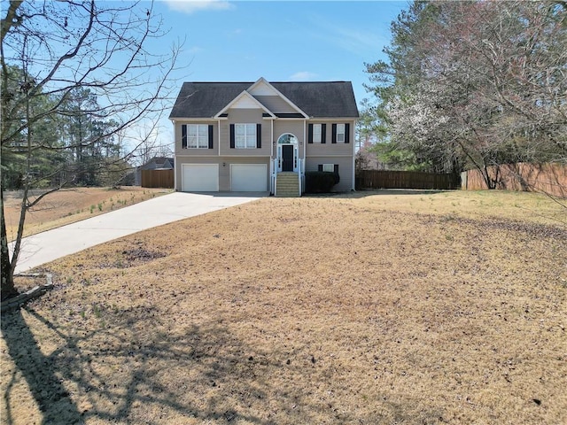 raised ranch with an attached garage, fence, and driveway