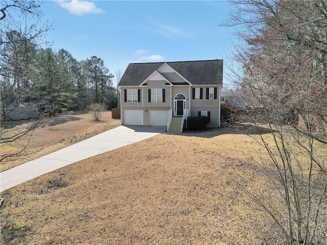 raised ranch with an attached garage and concrete driveway