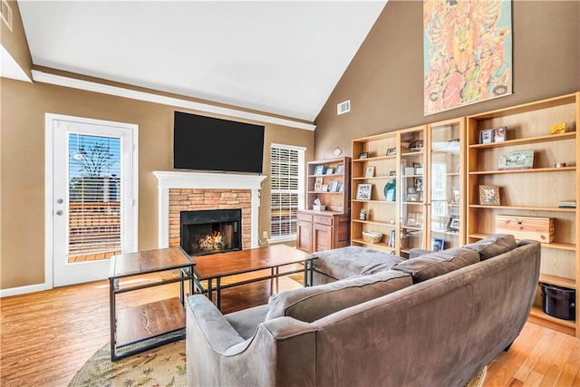 living area with a stone fireplace, light wood-style floors, visible vents, and baseboards