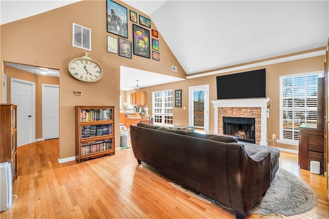 living area with visible vents, baseboards, light wood-style floors, and a stone fireplace