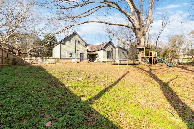 back of property with a playground, a yard, and a trampoline