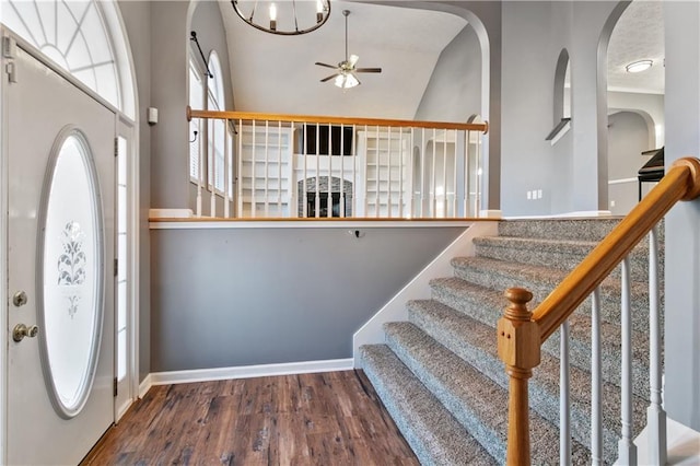 entryway featuring ceiling fan with notable chandelier, high vaulted ceiling, and dark wood-type flooring