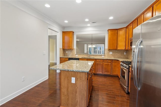 kitchen featuring dark wood-style flooring, brown cabinets, appliances with stainless steel finishes, and a sink