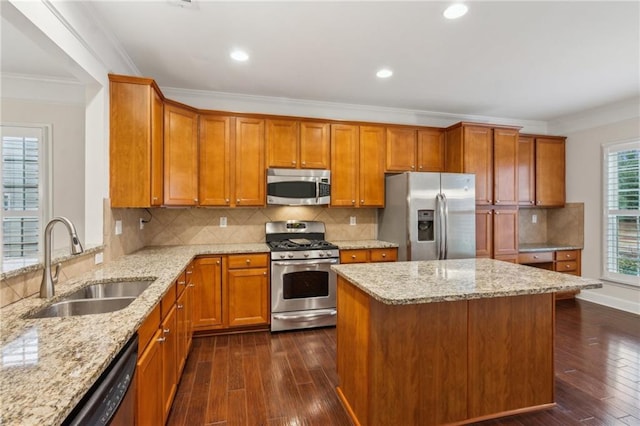 kitchen with dark wood-type flooring, ornamental molding, brown cabinetry, stainless steel appliances, and a sink