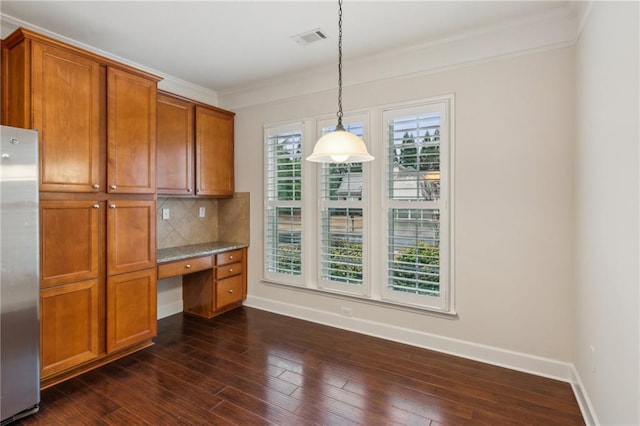 kitchen featuring visible vents, built in study area, freestanding refrigerator, brown cabinets, and backsplash