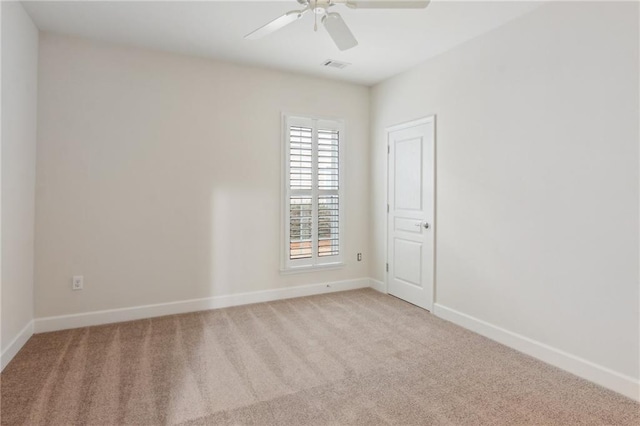 carpeted spare room with visible vents, a ceiling fan, and baseboards