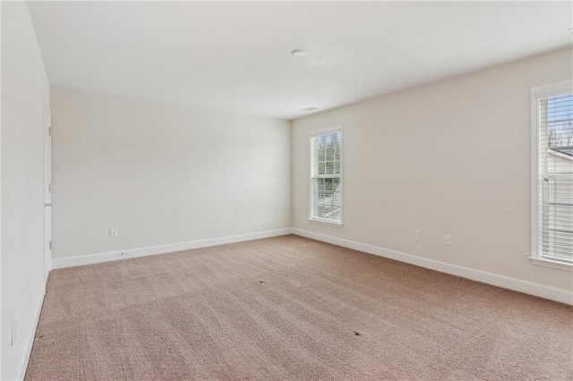 unfurnished room featuring baseboards and light carpet