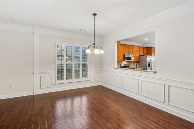 unfurnished dining area with a notable chandelier, ornamental molding, a decorative wall, and dark wood-style flooring