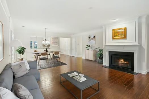 living area with a fireplace with flush hearth, an inviting chandelier, and wood finished floors