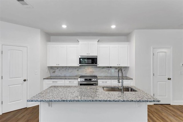 kitchen with dark wood-type flooring, white cabinets, tasteful backsplash, a sink, and stainless steel appliances