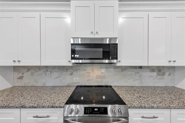 kitchen featuring white cabinets, stainless steel appliances, light stone counters, and tasteful backsplash