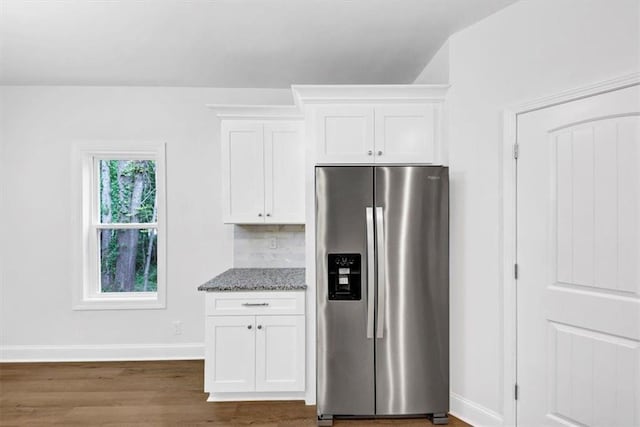 kitchen featuring white cabinets, light stone countertops, stainless steel fridge, baseboards, and dark wood-style floors