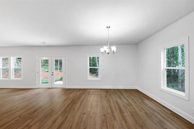 spare room featuring baseboards, a wealth of natural light, and wood finished floors