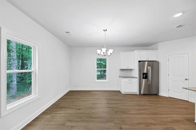 kitchen featuring white cabinets, a chandelier, stainless steel fridge, and a wealth of natural light