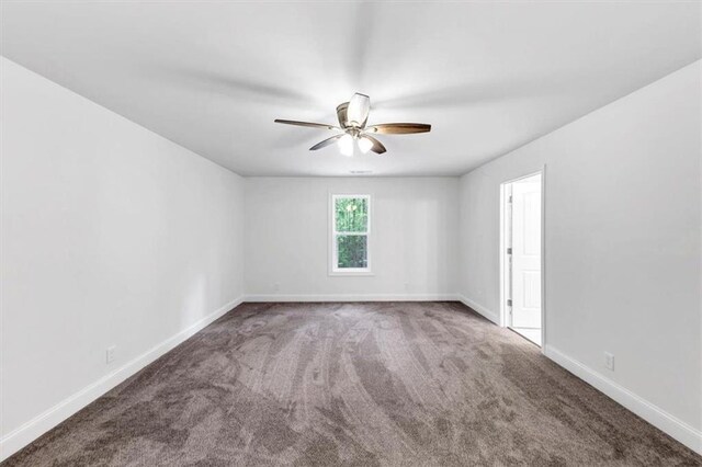 carpeted empty room featuring a ceiling fan and baseboards