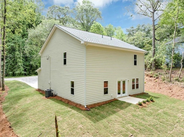 view of side of property with a yard, cooling unit, french doors, and a shingled roof