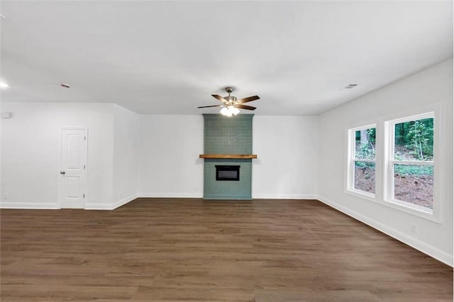 unfurnished living room featuring baseboards, ceiling fan, a fireplace, and wood finished floors