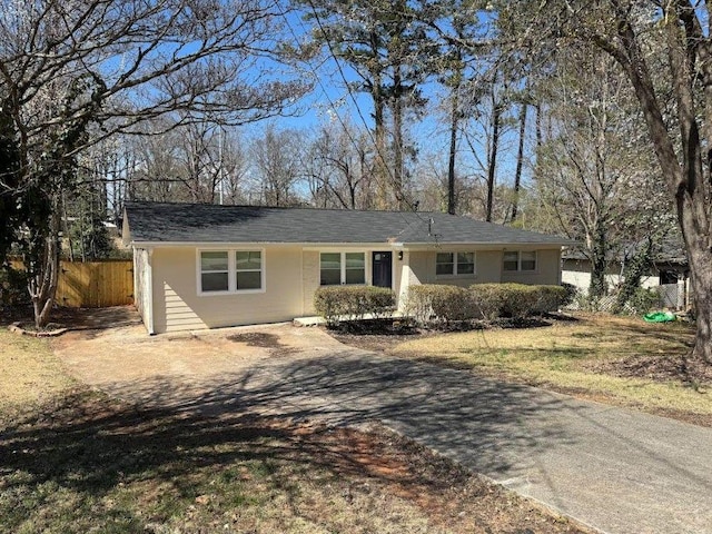 ranch-style home featuring driveway and fence