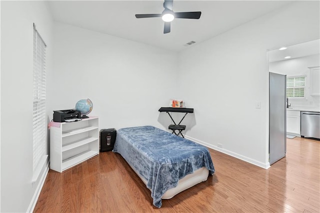 bedroom with light wood finished floors, baseboards, and a ceiling fan