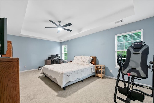 carpeted bedroom featuring a tray ceiling, baseboards, ceiling fan, and a desk