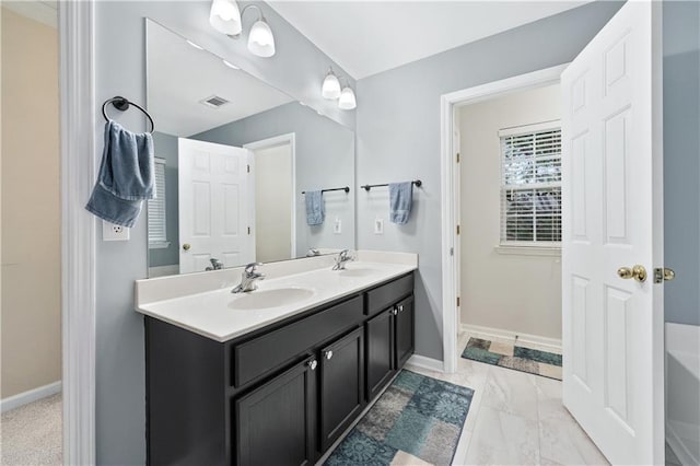 bathroom featuring baseboards, double vanity, and a bathtub