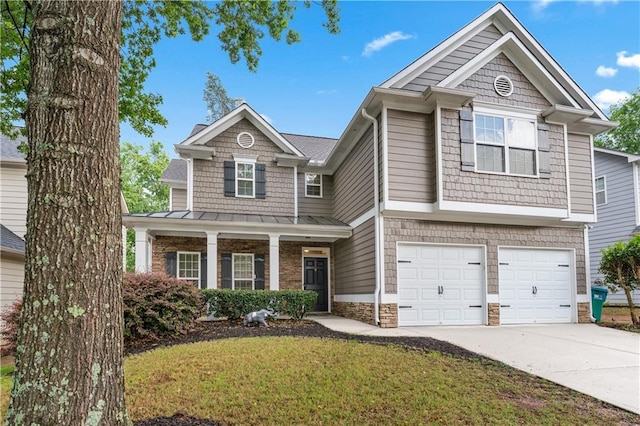 craftsman-style house featuring driveway, stone siding, a front yard, an attached garage, and a standing seam roof