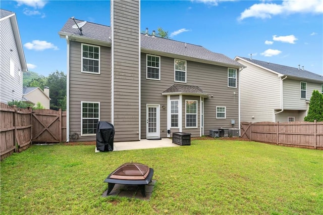 back of property with a chimney, a patio, a fire pit, and roof with shingles