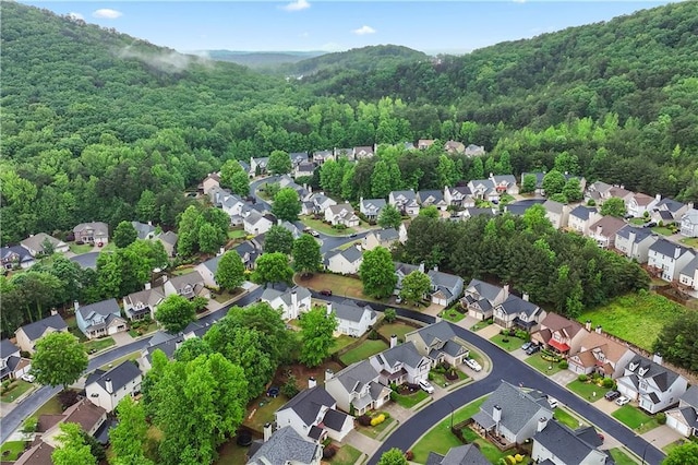 view of property location featuring a forest and nearby suburban area