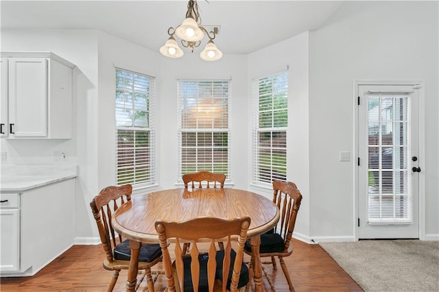 dining area featuring a chandelier, baseboards, and wood finished floors