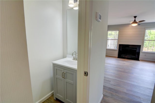 3263 Long Iron Pl, Lawrenceville, GA 30044 - bathroom featuring a ceiling fan, wood finished floors, vanity, a large fireplace, and baseboards