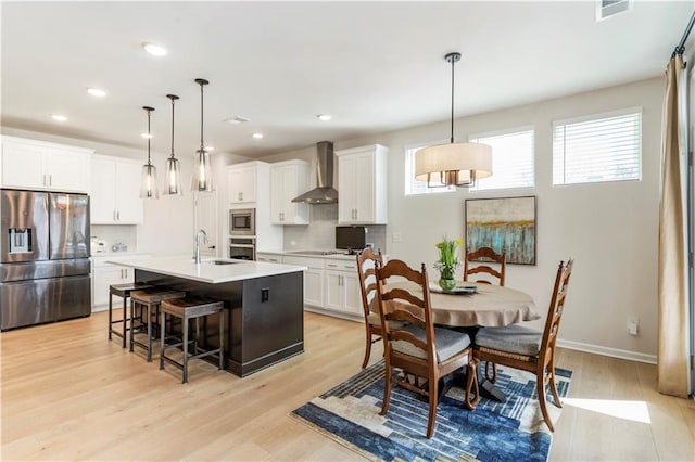15 Lakeside Way, Cartersville, GA 30121 - kitchen with appliances with stainless steel finishes, wall chimney range hood, a sink, light wood finished floors, and a kitchen bar