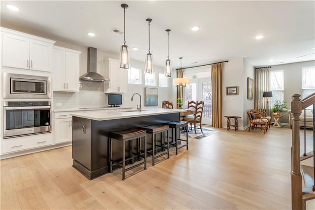 15 Lakeside Way, Cartersville, GA 30121 - kitchen with stainless steel appliances, wall chimney exhaust hood, a sink, a kitchen island with sink, and light countertops