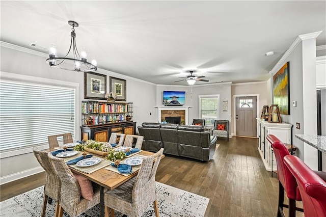 4571 Academy St, Acworth, GA 30101 - dining room featuring ornamental molding, a ceiling fan, a fireplace, a chandelier, and dark wood-type flooring