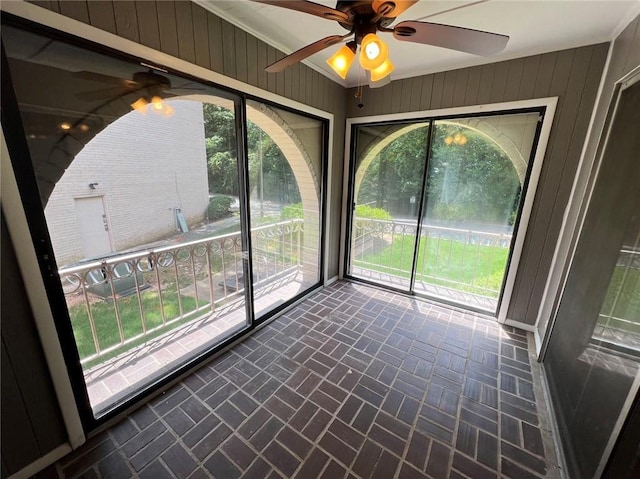 unfurnished sunroom featuring ceiling fan