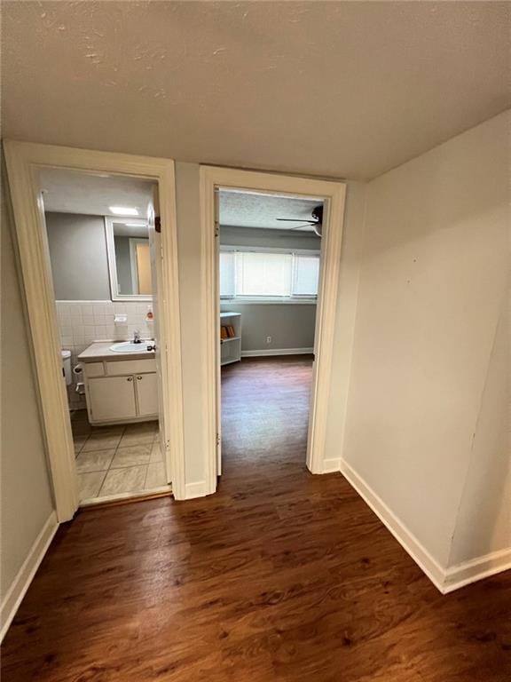 corridor with hardwood / wood-style flooring, sink, and a textured ceiling