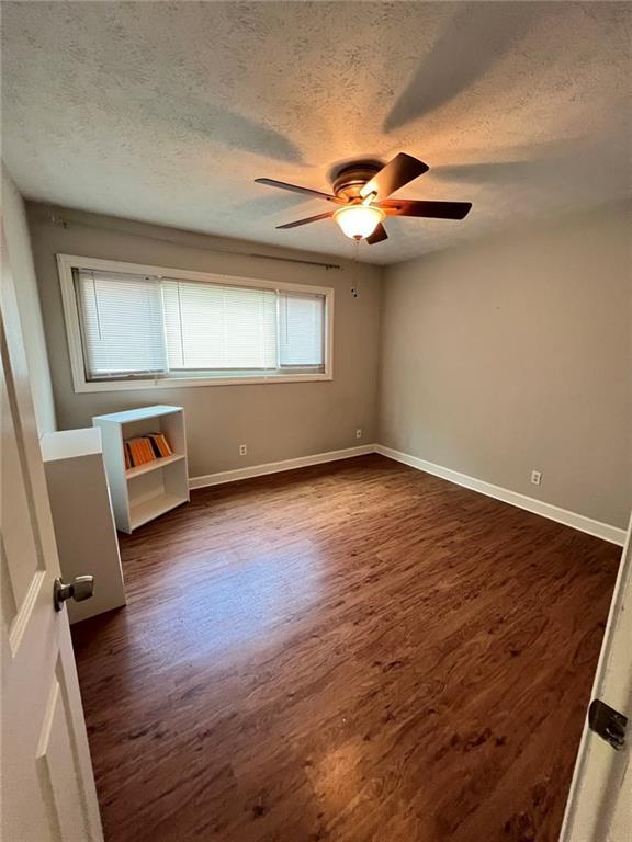 unfurnished room featuring a textured ceiling, dark hardwood / wood-style floors, and ceiling fan