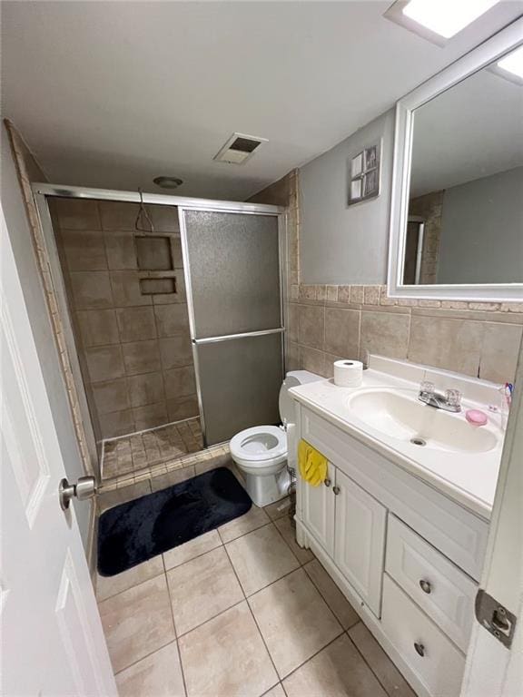 bathroom featuring tile walls, vanity, walk in shower, toilet, and tile patterned floors