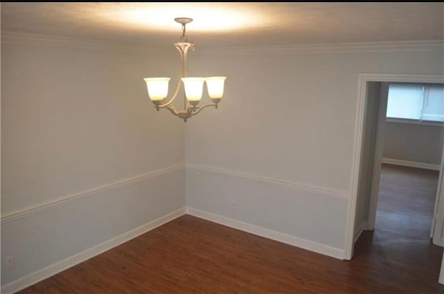 unfurnished room with ornamental molding, dark wood-type flooring, and an inviting chandelier