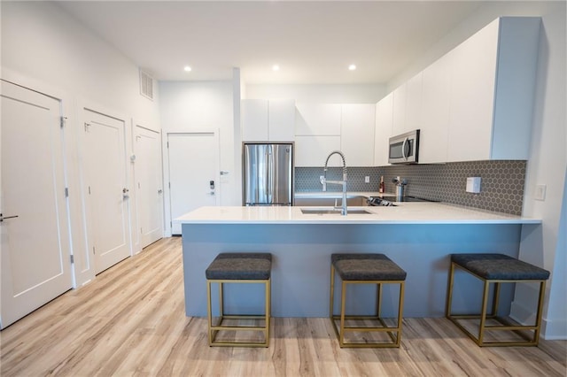 kitchen featuring appliances with stainless steel finishes, a breakfast bar, light hardwood / wood-style flooring, and sink