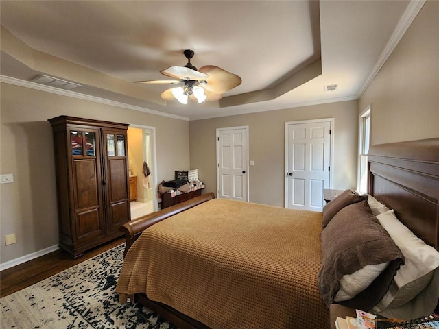 bedroom with baseboards, visible vents, dark wood finished floors, a tray ceiling, and crown molding