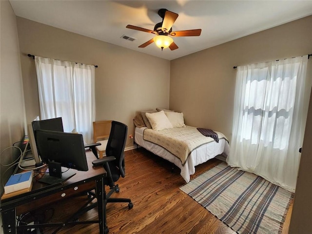 bedroom with dark wood-style floors, visible vents, and a ceiling fan