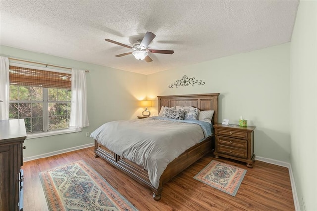 bedroom with ceiling fan, wood-type flooring, and a textured ceiling