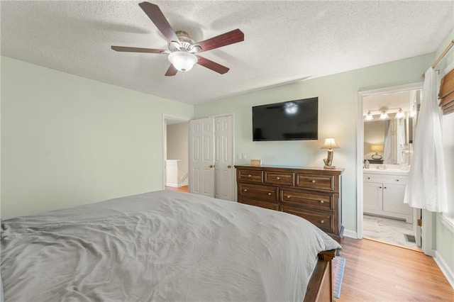 bedroom with ceiling fan, light hardwood / wood-style flooring, ensuite bathroom, a textured ceiling, and a closet