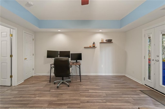 office space featuring wood-type flooring, a raised ceiling, and ceiling fan