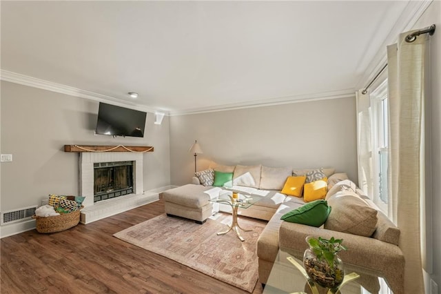 living room with crown molding, hardwood / wood-style floors, and a brick fireplace